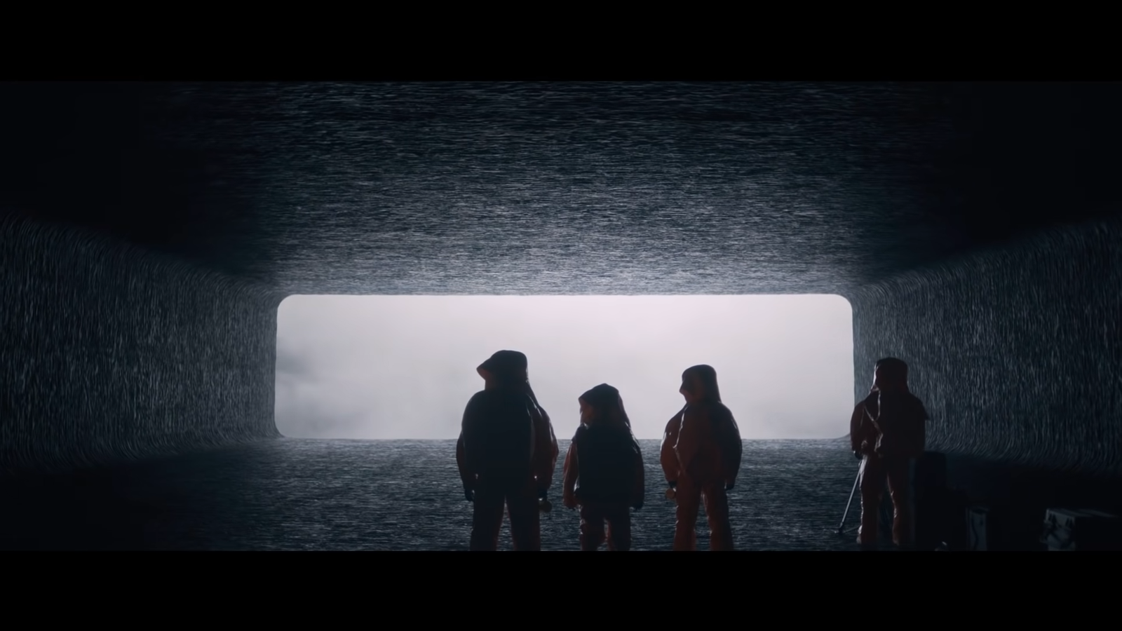 four characters stand in a dark tunnel